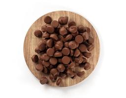 schokoladenstückchen, die auf rundes hölzernes tablettbrett fallen, draufsicht 3d-illustration foto
