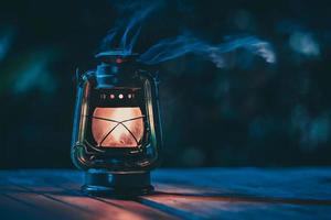 Antike Petroleumlampe mit Lichtern auf dem Holzboden auf dem Rasen in der Nacht