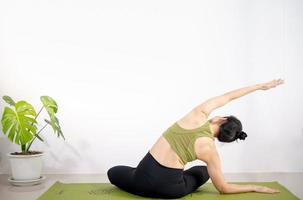 Frau, die Yoga auf der grünen Yogamatte macht, um zu Hause zu meditieren und zu trainieren. foto