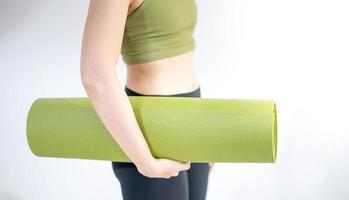 weibliche hand, die grüne yogamatte hält, um übung auf der matte vorzubereiten. foto