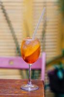 Vertikale Aufnahme von Aperol Spiritz Cocktail, der in den 1950er Jahren populär wurde. kaltes getränk mit eis und orange im weinglas mit strohhalm, um sich im heißen sommer frisch zu fühlen foto
