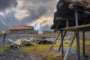 Baumstämme durch Schuppen und traditionelle Häuser, umgeben von Zaun im alten Wikingerdorf foto