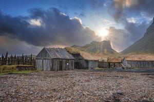 Verlassene Häuser, umgeben von einem Holzzaun unter dem Berg Vestrahorn bei Sonnenuntergang foto