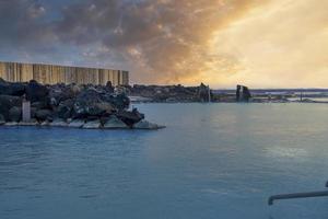 natürliches geothermalbad in der blauen lagune gegen bewölkten himmel während des sonnenuntergangs foto