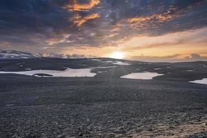 Malerischer Blick auf die Sonne, die während des Sonnenuntergangs über Schnee auf der Vulkanlandschaft scheint foto