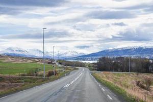 Malerischer Blick auf die leere Straße inmitten grüner Landschaft in Richtung Berge gegen den Himmel foto