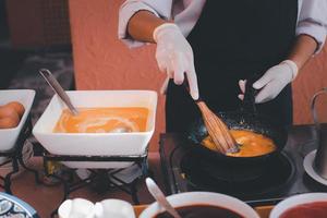 Küchenchef macht Frühstücks-Omeletts mit Eiern, Ketchup und Chili-Sauce als Beilage. foto