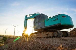 Baggerlader und Windturbinen, die im Hintergrund Strom erzeugen, das Konzept nachhaltiger Ressourcen, schöner Himmel mit Windgeneratoren, erneuerbare Energie foto