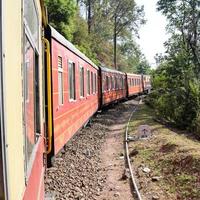 Spielzeugeisenbahn, die sich auf Berghängen bewegt, schöne Aussicht, ein Seitenberg, ein Seitental, das sich auf der Eisenbahn zum Hügel bewegt, inmitten grüner Naturwälder. Spielzeugeisenbahn von Kalka nach Shimla in Indien foto