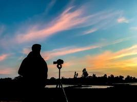 Mann mit Kamera-Shooting-Sonnenuntergang-Silhouette-Stil. foto