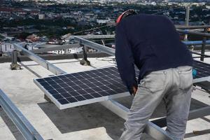 Der Techniker bohrt Löcher, um die Solarzelle mit einer elektrischen Bohrmaschine auf dem Dach zu montieren. foto