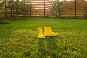 gelbe stiefel stehen auf grünem rasen im frühlingsgartenkopierraum und platz für werbung - sommer- und landlebenskonzept foto