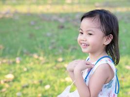 positives charmantes 4 Jahre altes süßes asiatisches Mädchen, kleines Vorschulkind, das lächelt und nach links schaut foto
