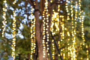 Unscharfes Bild dekorative Lichterketten im Freien, die nachts am Baum im Garten hängen foto