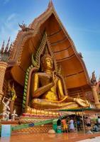 kanchanaburi, thailand - 12. juni 2021 leute kommen, um zu beten und anzubeten, um goldene buddha-statue im tigerhöhlentempel oder wat tham sua zu bieten, neue normale soziale distanzierung für reisen foto