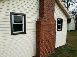 Haus mit neuen Fenstern installiert und dunkler Verkleidung und gemauertem Schornstein foto