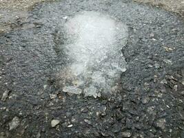 Eisschmelze auf schwarzem Asphalt oder Pflaster foto