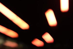 Defokussierte Neonlichter auf schwarzem Hintergrund. verschwommenes stadtlicht in oranger und roter farbe foto