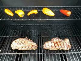 Steaks auf dem Grill mit bunten Paprika foto