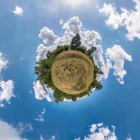 kleiner Planet. sphärische ansicht in einem feld an einem schönen tag mit schönen wolken foto