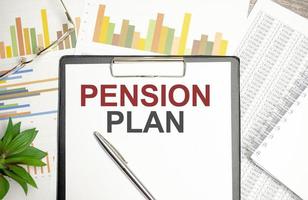 Sticker, Pflanze, Kugelschreiber und ein weißes Notizbuch mit dem Text Pensionsplan foto