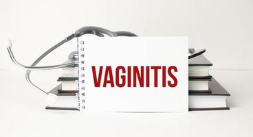 Vaginitis-Wort auf Notizblock und Stethoskop auf weißem Hintergrund foto