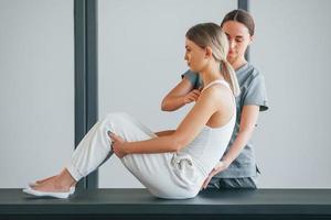 Bauchmuskeln machen. frau ist im gesundheitszentrum und bekommt hilfe vom arzt foto