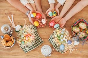 Draufsicht der Hände auf dem Tisch. glückliche familie, die zusammen osterferien feiert foto