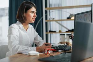 Anzeige betrachten. Designerin, die im Büro arbeitet, indem sie einen PC verwendet foto