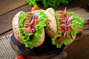Hotdog mit Ketchup-Senf und Salat auf hölzernem Hintergrund. foto