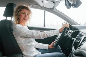 Seitenansicht. frau mit lockigen blonden haaren ist im autosalon foto