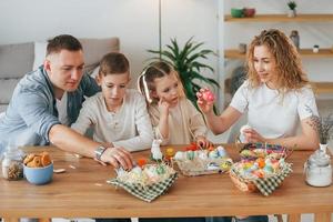 am Tisch sitzen. glückliche familie, die zusammen osterferien feiert foto