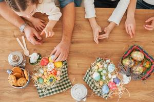 Draufsicht der Hände auf dem Tisch. glückliche familie, die zusammen osterferien feiert foto