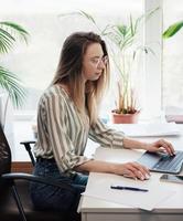 junge Frau, die an einem Computer arbeitet foto