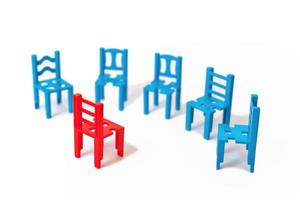 Coaching-Konzept. Gruppe von blauen Stühlen und einem roten Stuhl davor isoliert. Gruppentherapie Sitzung. foto