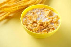 Milch in Cornflakes auf gelbem Hintergrund gießen foto
