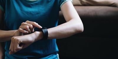glückliche frau, die smartwatch verwendet, um ergebnisse in der fitness-app zu überprüfen. gesundes lebensstilkonzept. foto