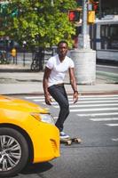 schwarzer Junge, der mit Longboard auf der Straße skatet foto