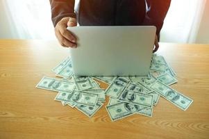 Geschäftsmann arbeitet am Laptop mit Geld auf dem Schreibtisch des Finanziers Finanziell erfolgreicher Geschäftsmann foto