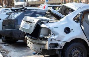 Viele kaputte Autos nach einem Verkehrsunfall auf dem Parkplatz einer Restaurierungswerkstatt auf der Straße. Karosserieschadenwerkstatt im Freien. Verkauf von Versicherungs-Einsatzfahrzeugen auf einer Auktion. foto