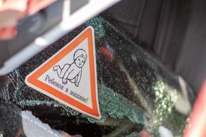 Warnzeichen von Kindern in einem Auto nach einem Unfall mit blutigen Glasscherben. übersetzung kind im auto. Nahaufnahme des weißen Baby-an-Bord-Aufklebers auf der Heckscheibe des Autos. foto