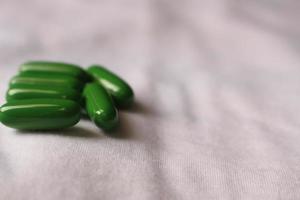 flacher Fokus Nahaufnahme von grünen Pillen auf einem weißen Stoff foto