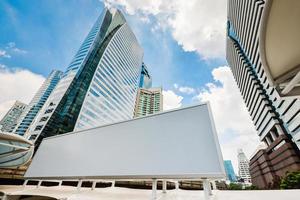 leere weiße Werbetafel mit modernen City-Business-Center-Gebäuden im Hintergrund mit blauem Himmel. foto