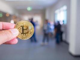 Hand einer kaukasischen jungen Frau, die eine Bitcoin-Kryptowährungsmünze hält foto