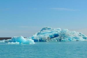 Heller klarer blauer Eisberg, der im blauen kalten Wasser des Jokulsarlon-Sees in Island schwimmt 42 foto