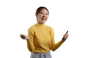 Porträt einer schönen asiatischen Frau in einem gelben Hemd, die auf einem Smartphone spielt. Porträtkonzept für Werbung und Beschilderung, isoliert über dem leeren Hintergrund, Kopierraum. foto
