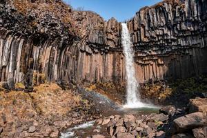 schöne kaskaden des svartifoss-wasserfalls und des fließenden stroms im nationalpark foto