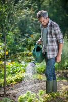 Porträt eines Gärtners, der seinen Garten bewässert foto