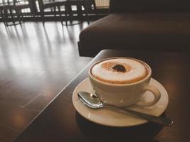 schaumiger kaffee und edelstahllöffel werden im café auf den tisch gestellt.kopierraum foto