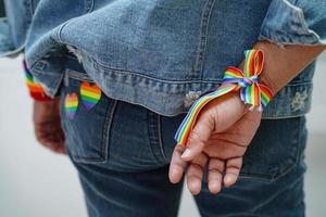 asiatische dame mit regenbogenflaggenarmbändern, symbol des lgbt-stolzmonats, feiert jährlich im juni die sozialarbeit von schwulen, lesbischen, bisexuellen, transgendern und menschenrechten. foto